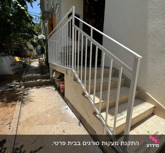מעקה מתכת לבן על מדרגות חיצוניות